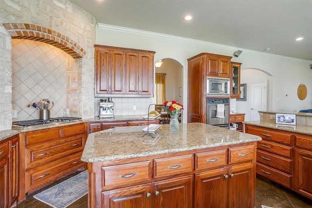kitchen featuring arched walkways, a kitchen island, stainless steel appliances, and tasteful backsplash