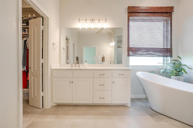 bathroom with ceiling fan, a freestanding tub, vanity, tile patterned floors, and a spacious closet