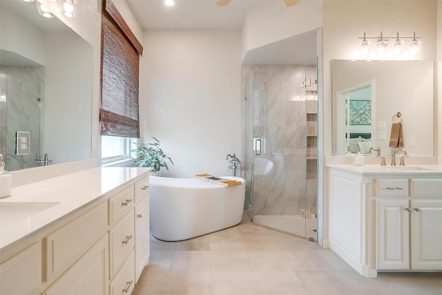 full bath featuring a freestanding bath, tile patterned flooring, a stall shower, two vanities, and a sink
