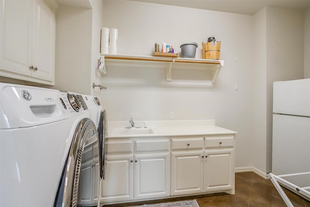 washroom with a sink, baseboards, cabinet space, and washing machine and clothes dryer
