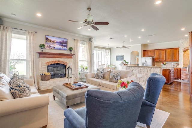 living area with crown molding, recessed lighting, ceiling fan, and a fireplace