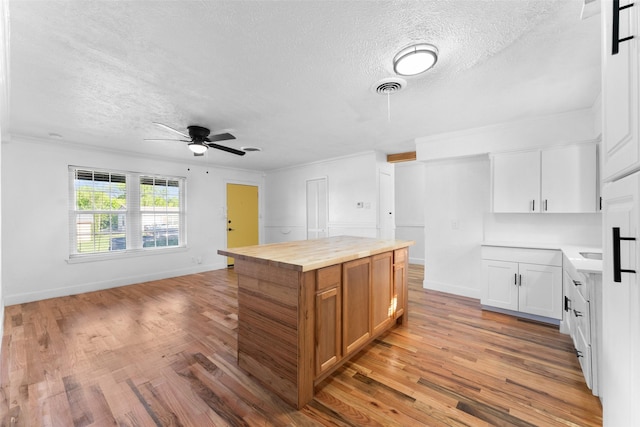 1909 Sycamore Dr, Mesquite, TX 75149 - kitchen with wooden counters, a textured ceiling, light wood-style floors, ceiling fan, and a center island