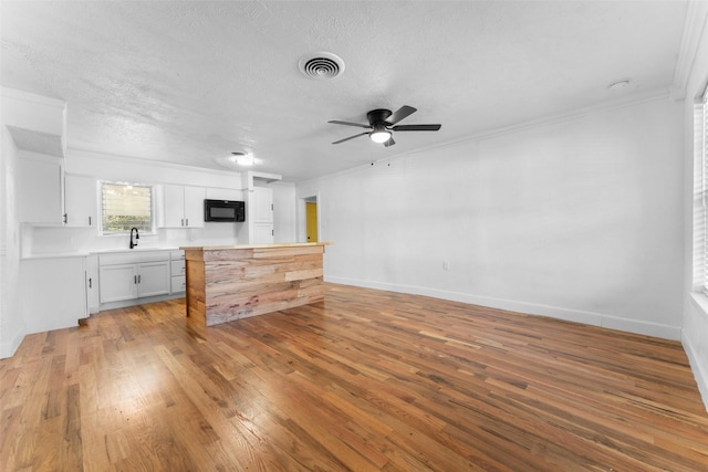 1909 Sycamore Dr, Mesquite, TX 75149 - unfurnished living room featuring light wood-style floors, a textured ceiling, a ceiling fan, a sink, and crown molding