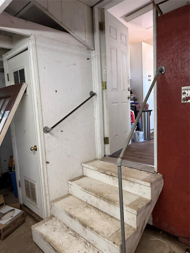 staircase featuring visible vents and unfinished concrete flooring
