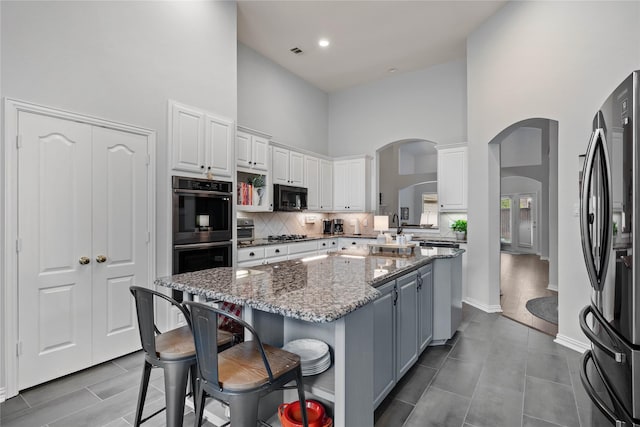 953 Waterbury Way, Keller, TX 76248 - kitchen with a high ceiling, black microwave, arched walkways, a center island, and white cabinets