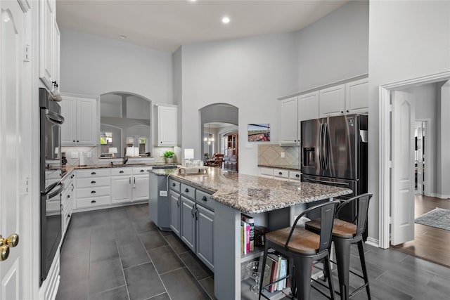 953 Waterbury Way, Keller, TX 76248 - kitchen featuring appliances with stainless steel finishes, a high ceiling, a center island, arched walkways, and white cabinetry
