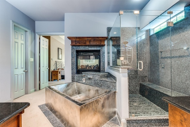 full bath featuring vanity, a multi sided fireplace, and a stall shower