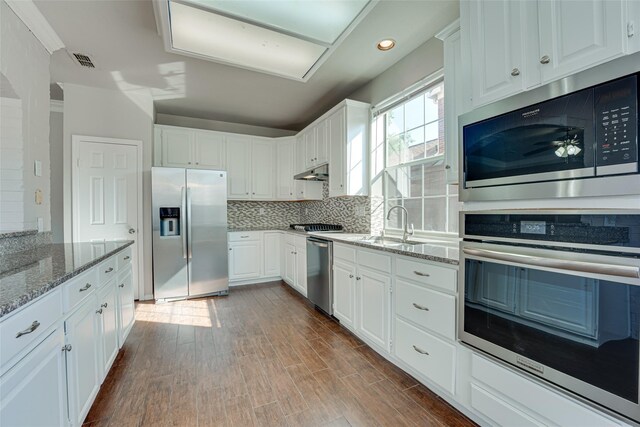 4032 Guthrie Dr, Plano, TX 75024 - kitchen featuring stainless steel appliances, backsplash, light stone counters, white cabinets, and under cabinet range hood