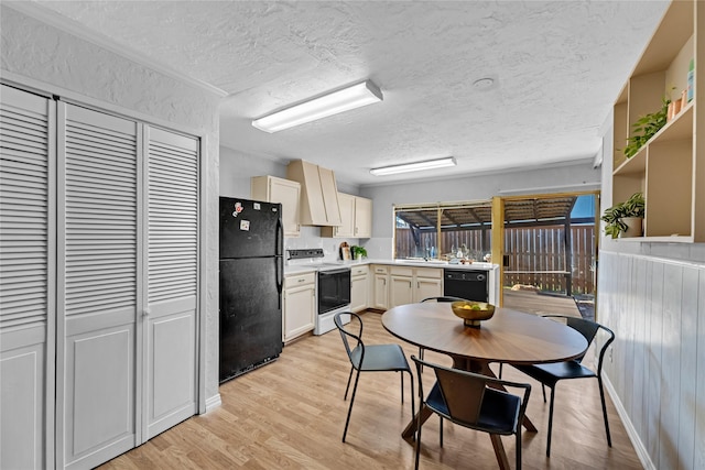 kitchen with a sink, light countertops, a textured ceiling, light wood-style flooring, and black appliances