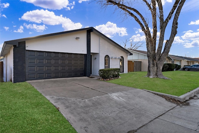 view of front of house with brick siding, an attached garage, a front yard, and concrete driveway