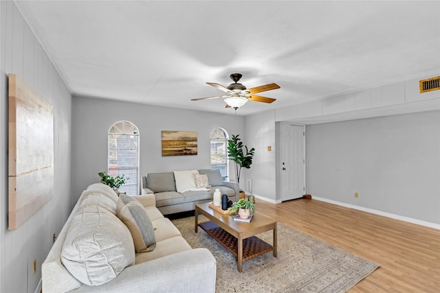 living area with light wood-type flooring, a ceiling fan, baseboards, and visible vents