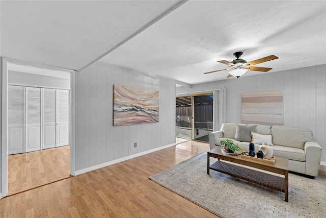 living area featuring baseboards, ceiling fan, and wood finished floors