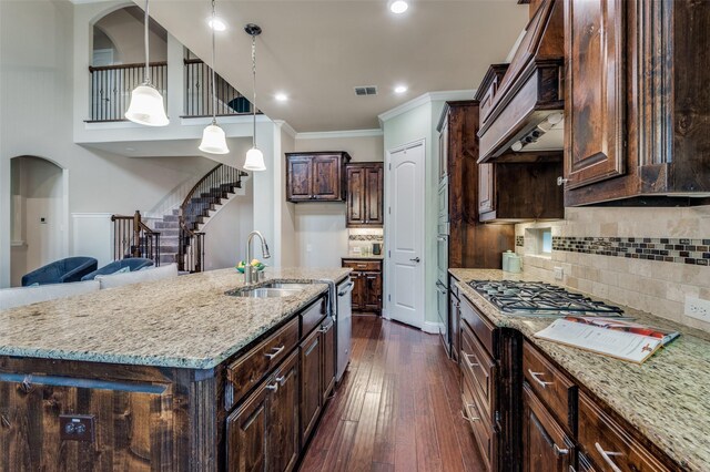 kitchen with dark brown cabinets, light stone countertops, a sink, visible vents, and ornamental molding