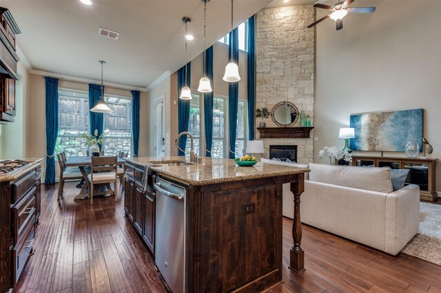 kitchen featuring dark wood-style flooring, a sink, a fireplace, stainless steel dishwasher, and visible vents