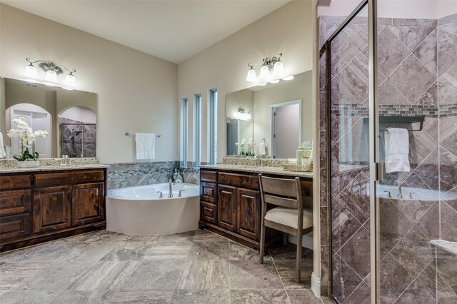 full bathroom featuring a sink, a stall shower, a garden tub, and two vanities