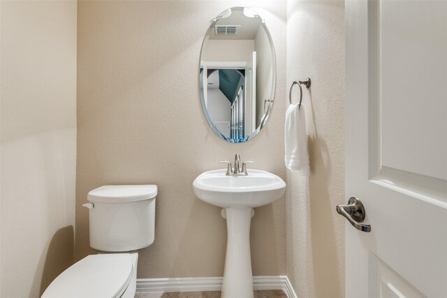 half bath featuring a sink, toilet, and visible vents