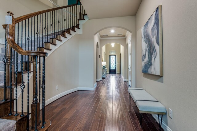 entryway with visible vents, arched walkways, hardwood / wood-style flooring, baseboards, and stairs