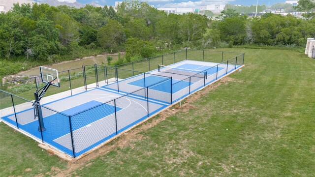 view of sport court with a lawn, a tennis court, fence, and community basketball court