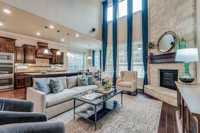 living room with crown molding, a high ceiling, a fireplace, and dark wood-type flooring