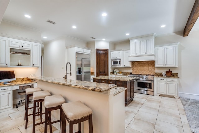 2890 Creekwood Ln, Prosper, TX 75078 - kitchen with built in appliances, a kitchen island with sink, tasteful backsplash, a kitchen bar, and white cabinetry