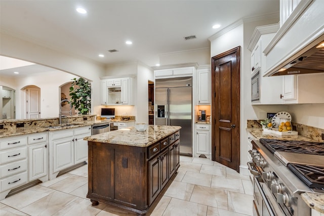 2890 Creekwood Ln, Prosper, TX 75078 - kitchen with appliances with stainless steel finishes, premium range hood, white cabinets, dark brown cabinetry, and ornamental molding