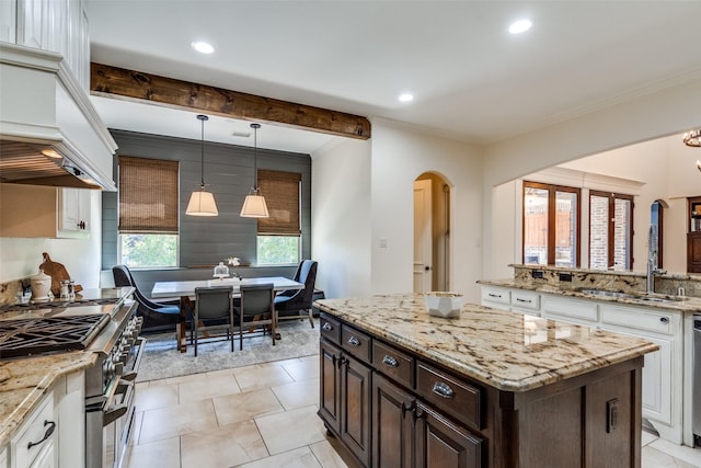 2890 Creekwood Ln, Prosper, TX 75078 - kitchen featuring range with two ovens, arched walkways, white cabinetry, crown molding, and custom exhaust hood