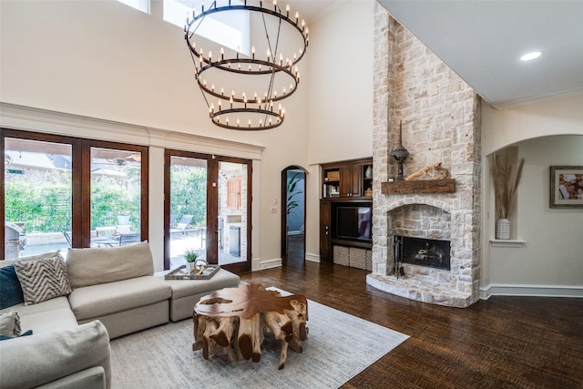 2890 Creekwood Ln, Prosper, TX 75078 - living area featuring arched walkways, a chandelier, a stone fireplace, wood finished floors, and crown molding
