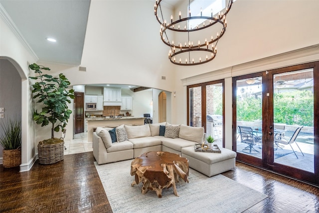 2890 Creekwood Ln, Prosper, TX 75078 - living area featuring arched walkways, french doors, ornamental molding, a chandelier, and a high ceiling