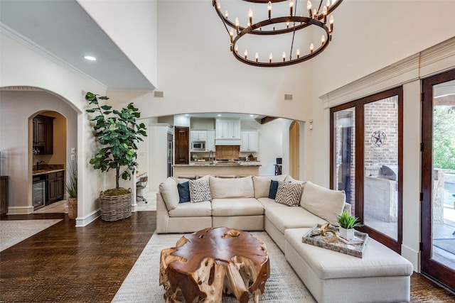 2890 Creekwood Ln, Prosper, TX 75078 - living room featuring arched walkways, a chandelier, dark wood-style flooring, wine cooler, and crown molding