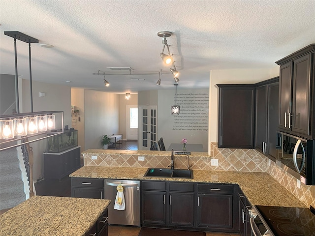 9140 Blackstone Dr, Providence Village, TX 76227 - kitchen featuring light stone countertops, a peninsula, appliances with stainless steel finishes, a sink, and decorative backsplash