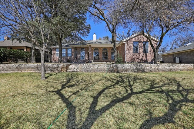 view of front of house with a chimney, a front lawn, and brick siding