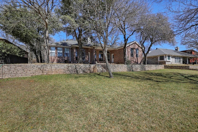 back of property with a yard and brick siding