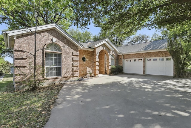 single story home featuring a garage, brick siding, and driveway