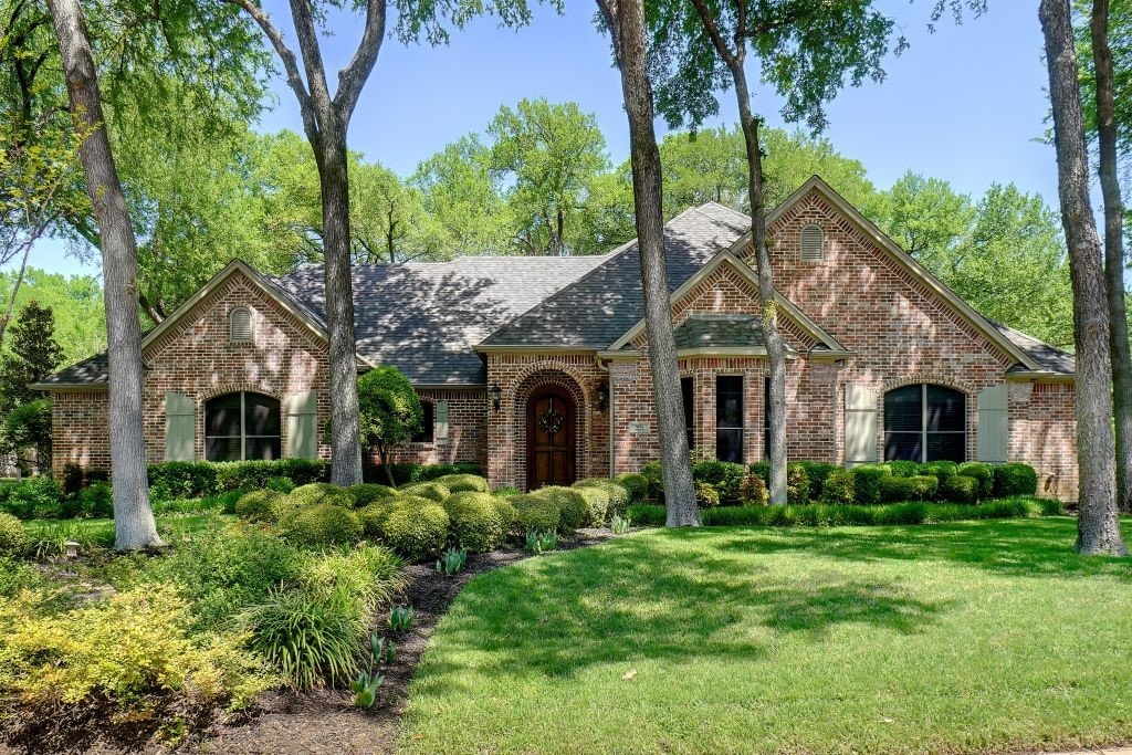view of front of house with a shingled roof, a front lawn, and brick siding