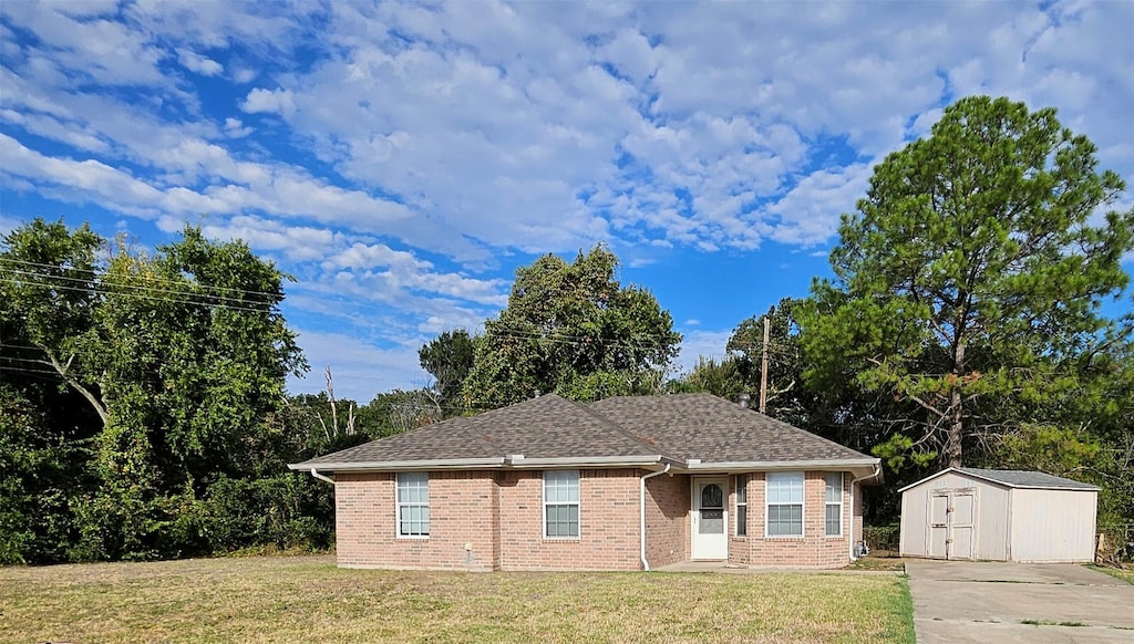 127 S Oak St, Lacy Lakeview, TX 76705 - view of front facade featuring a shingled roof, brick siding, a shed, an outbuilding, and a front lawn