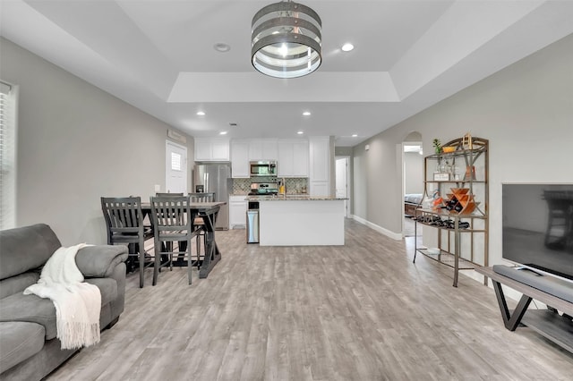 530 E Day St, Denison, TX 75021 - living room with baseboards, recessed lighting, a tray ceiling, arched walkways, and light wood finished floors
