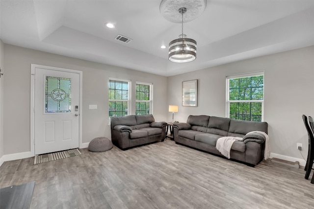 530 E Day St, Denison, TX 75021 - living room featuring a raised ceiling, a chandelier, wood finished floors, and a healthy amount of sunlight