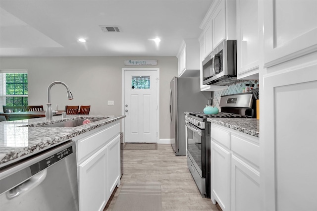 530 E Day St, Denison, TX 75021 - kitchen featuring light stone counters, white cabinets, visible vents, appliances with stainless steel finishes, and a sink