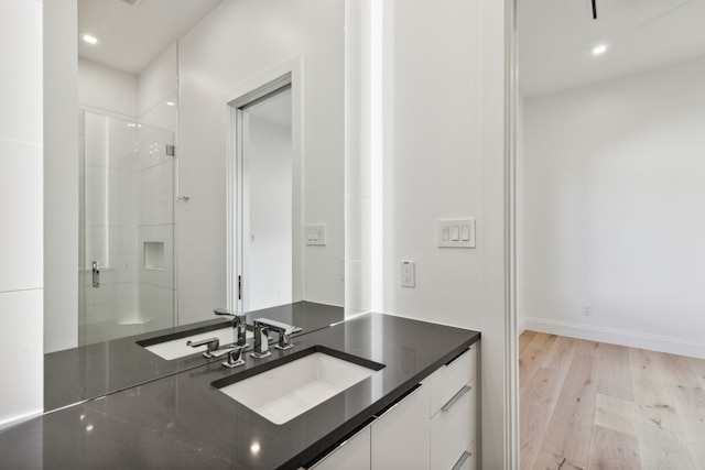 full bath featuring a shower with door, recessed lighting, baseboards, vanity, and wood finished floors