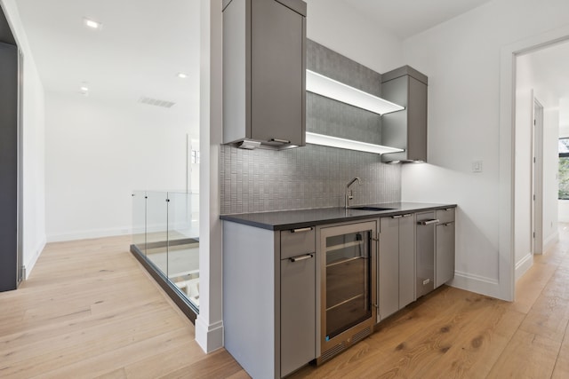 bar with light wood-style flooring, a sink, visible vents, decorative backsplash, and wine cooler