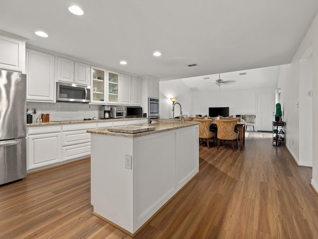 6504 Lago Vista Dr, Benbrook, TX 76132 - kitchen with tasteful backsplash, white cabinetry, a kitchen island with sink, appliances with stainless steel finishes, and wood finished floors