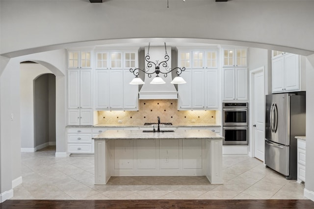 7217 Deer Field Dr, Mansfield, TX 76063 - kitchen with stainless steel appliances, arched walkways, tasteful backsplash, and a center island with sink