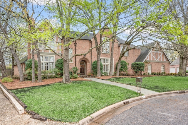 view of front facade with brick siding and a front lawn