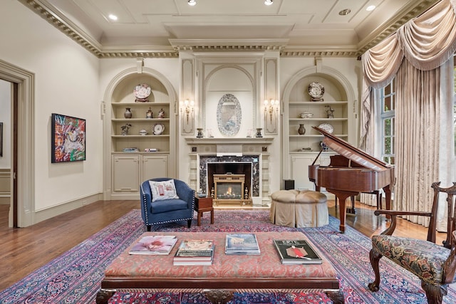 sitting room featuring crown molding, built in features, wood finished floors, and baseboards