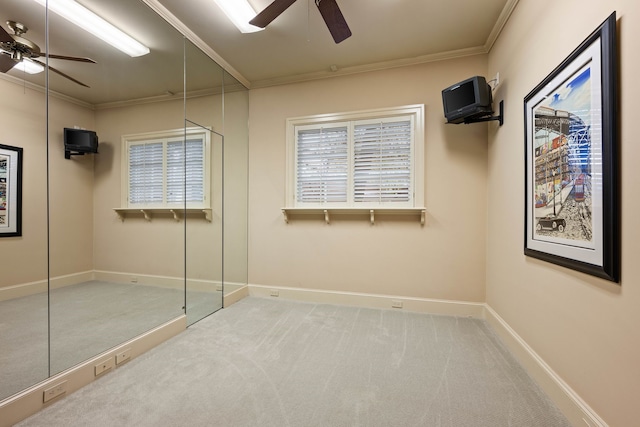 unfurnished bedroom featuring crown molding, carpet floors, baseboards, and ceiling fan
