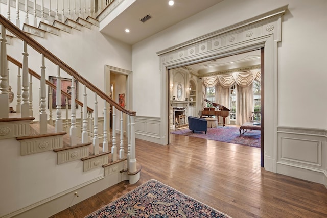 entrance foyer with a decorative wall, a wainscoted wall, wood finished floors, and stairs