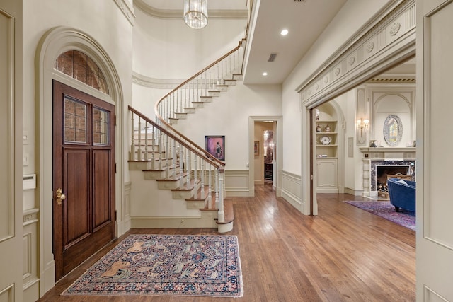 foyer with a wainscoted wall, stairs, wood finished floors, a decorative wall, and a premium fireplace