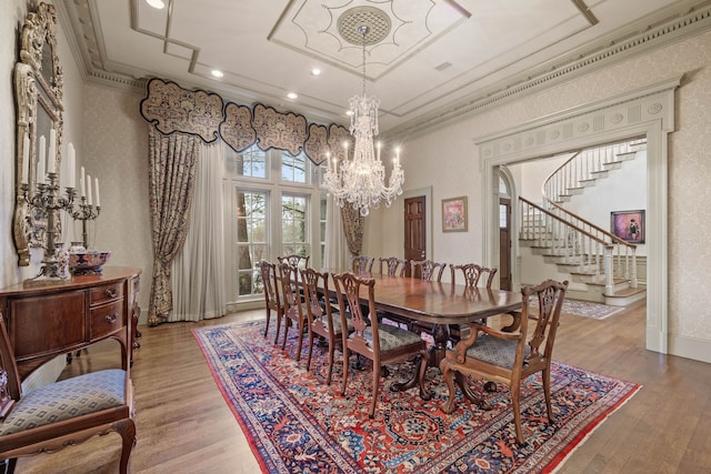 dining room with crown molding, an inviting chandelier, recessed lighting, wood finished floors, and stairs