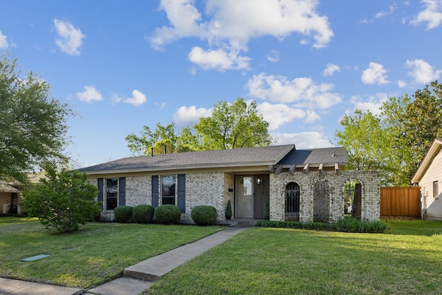 ranch-style house with a front yard, fence, and brick siding