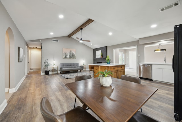 dining area with visible vents, a ceiling fan, lofted ceiling with beams, and a fireplace